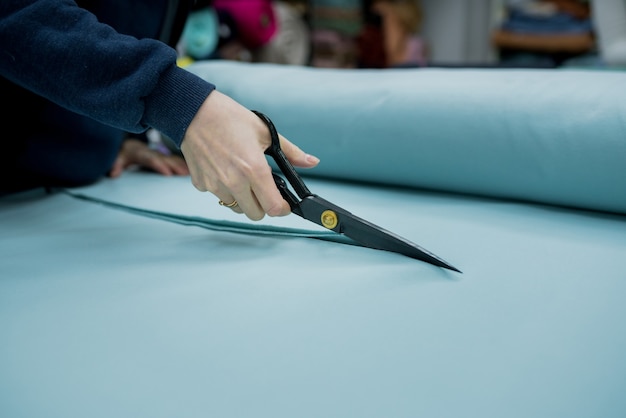 Close up of seller cutting fabrics in textile store Seamstress using scissors to trim the material