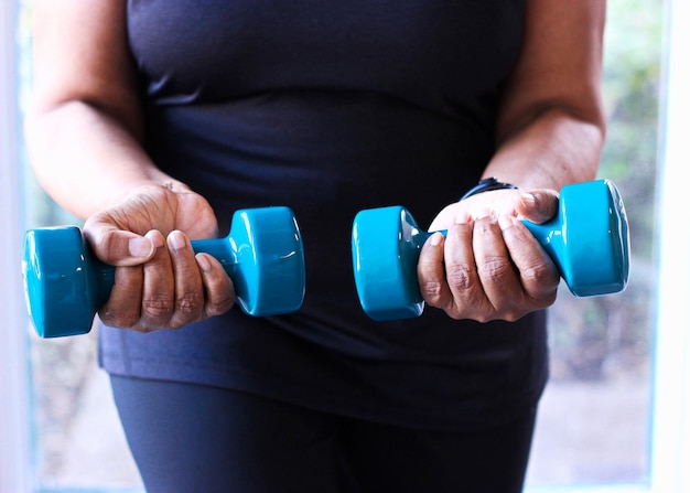 Photo close-up of senior black woman strength training with dumbbells for health and fitness