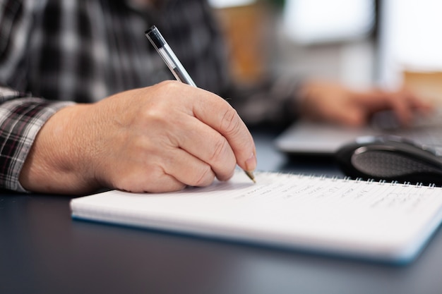 Close up of senior business woman writing notes