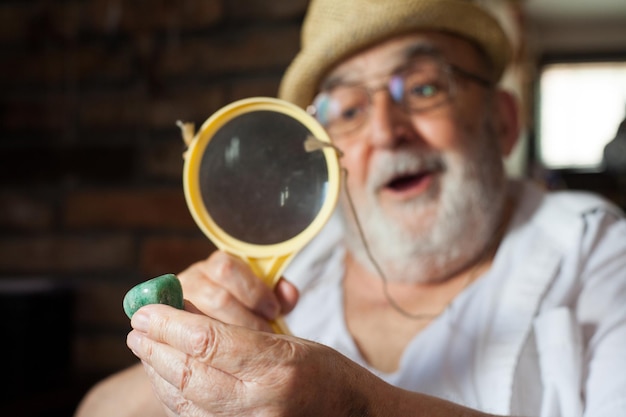 Foto close-up di un uomo anziano che guarda un ciottolo attraverso una lente di ingrandimento