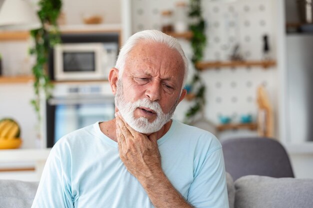 Photo close up of senior man rubbing his inflamed tonsils tonsilitis problem cropped man with thyroid gland problem touching his neck has a sore throat