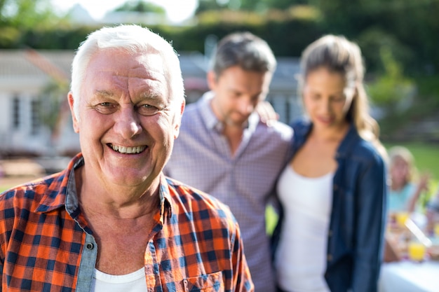 Photo close-up of senior man with couple in background