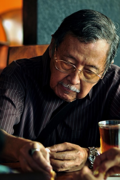 Close-up of senior man with drink on table in restaurant