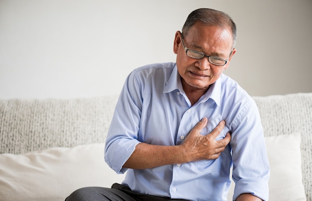 Close Up senior mannelijke Aziatische lijden aan hevige pijn in zijn hartaanval op de borst thuis. Gezondheidszorg en medisch concept van senior hart-en vaatziekten.