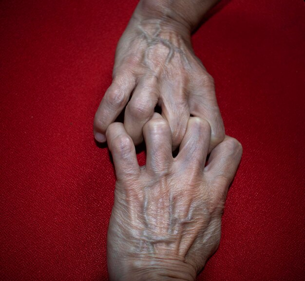 Photo close-up of senior person hand on red table