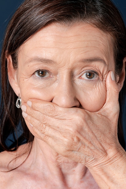 Photo close up of senior woman covering her mouth