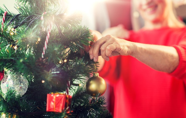 クリスマスツリーを飾っている上級女性のクローズアップ