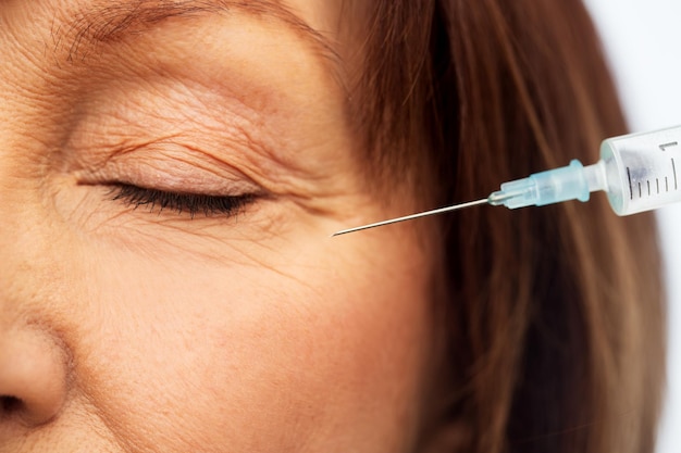 close up of senior woman face and syringe