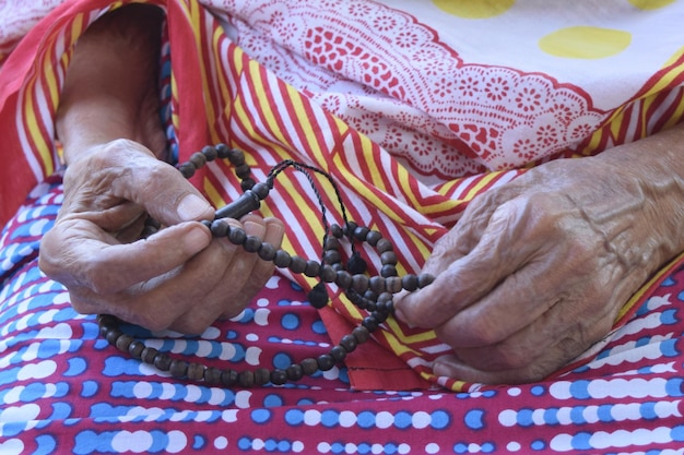 Foto close-up di una donna anziana che tiene delle perle di preghiera