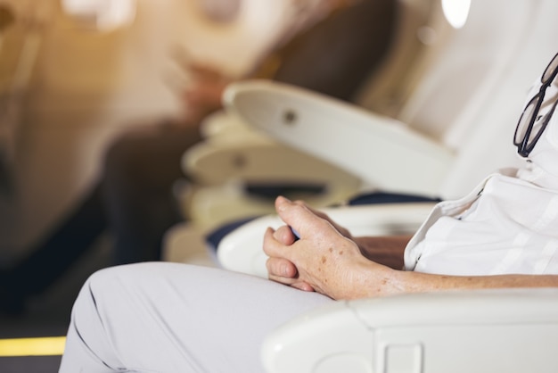 Close up Senior Woman's Hand sit on airplane