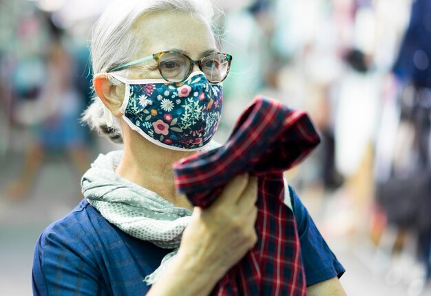 Photo close-up of senior woman wearing mask standing at store