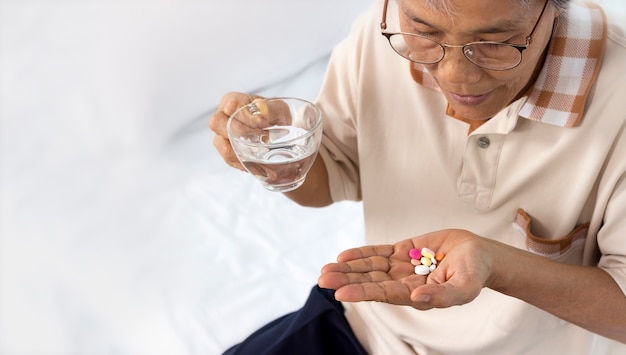 close up of senior woman with pills and glass of water at home