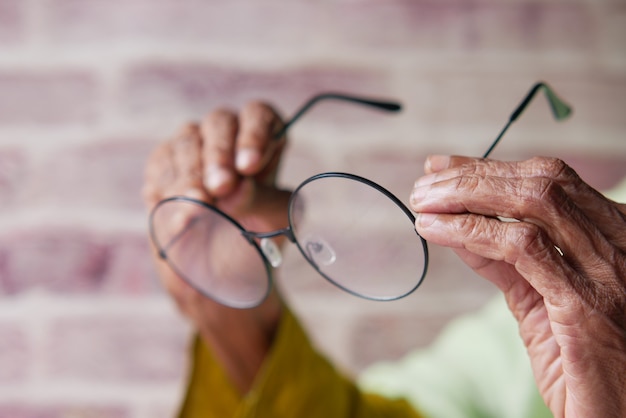 Close up of senior women hand holding old eyeglass