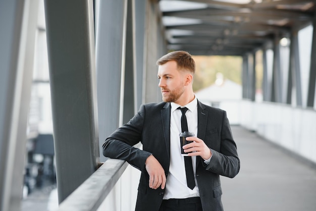 Close up serious businessman drinking take away coffee at
street portrait of business man waiting with coffee to go outdoor
office employee looking away at street male professional take
break