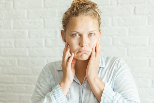 カメラを見ながら両手で彼女の顔に触れている深刻な動揺の女性をクローズアップ