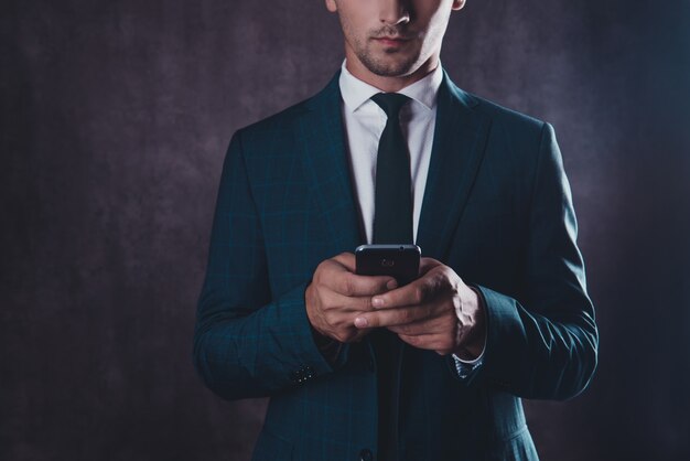 Close up of serious young successful man typing message on phone