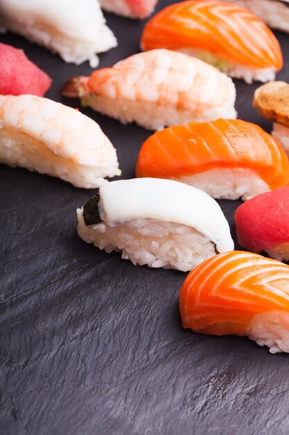 Close-up of set of four sushi with salmon, tuna, scallop and shrimp on a black background