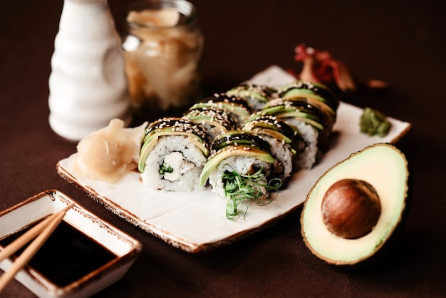 Close-up of a set of sushi rolls with an avocado cut in half lying next to it