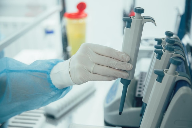 Close up of several micro pipettes. Hand in rubber glove taking one pipette