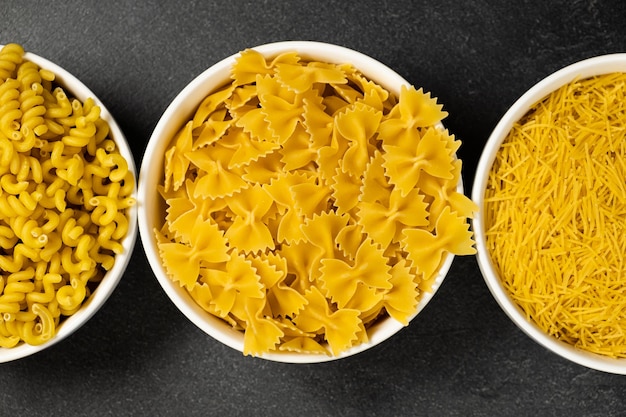 Close up of several types of dry pasta in a plate on dark background