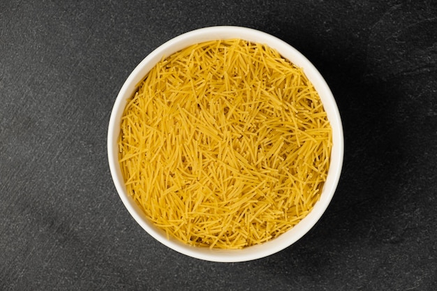 Close up of several types of dry pasta in a plate on dark background