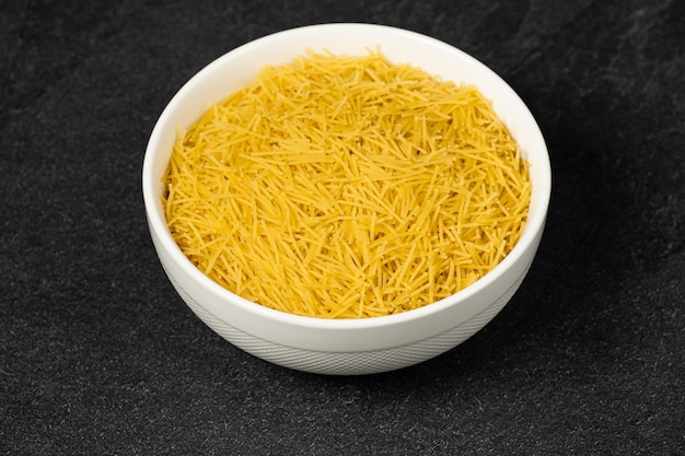 Close up of several types of dry pasta in a plate on dark background
