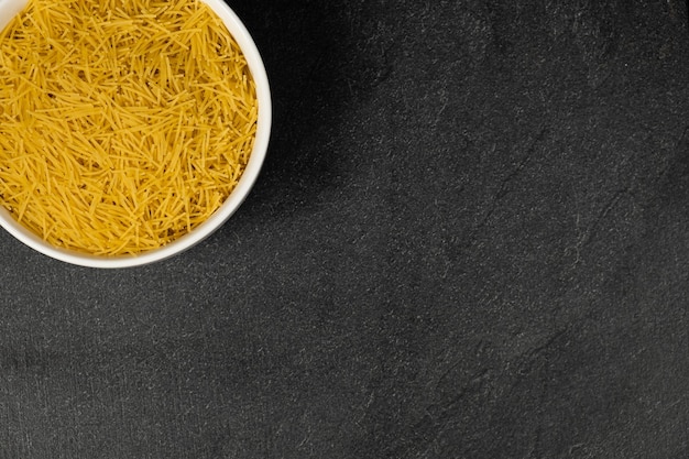 Close up of several types of dry pasta in a plate on dark background