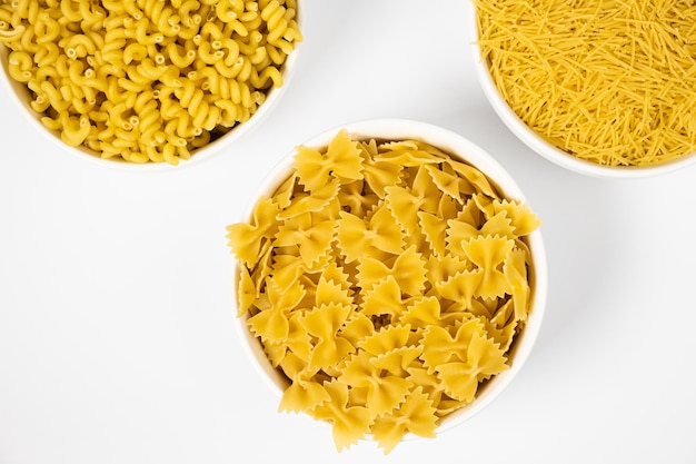 Close up of several types of dry pasta in a plate on white background