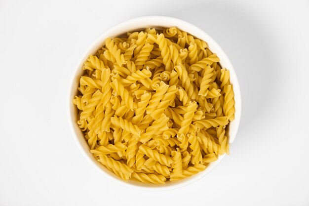 Close up of several types of dry pasta in a plate on white background