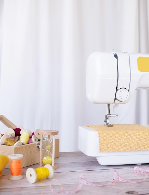 Photo close up sewing machine working with yellow fabric sewing accessories on the table stitch new clothing