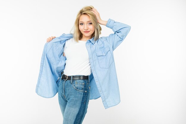 Close-up of a sexy attractive girl in a blue denim shirt and white t-shirt posing on a white studio