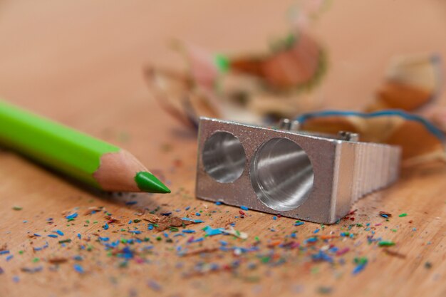 Close-up of sharpener and colored pencil with shavings