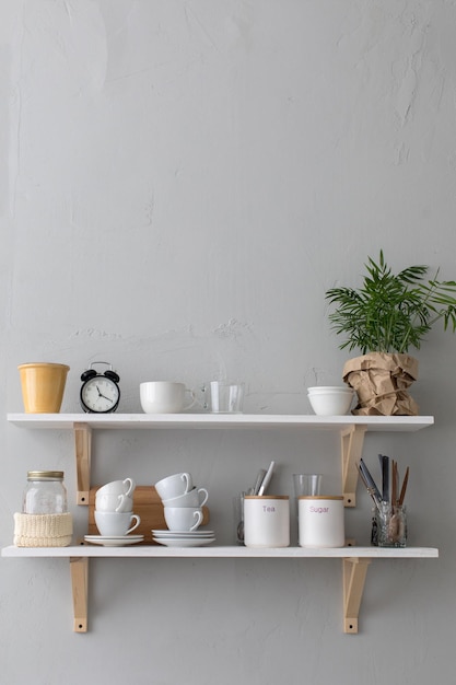 Photo close-up shelf with cups and different utensils.