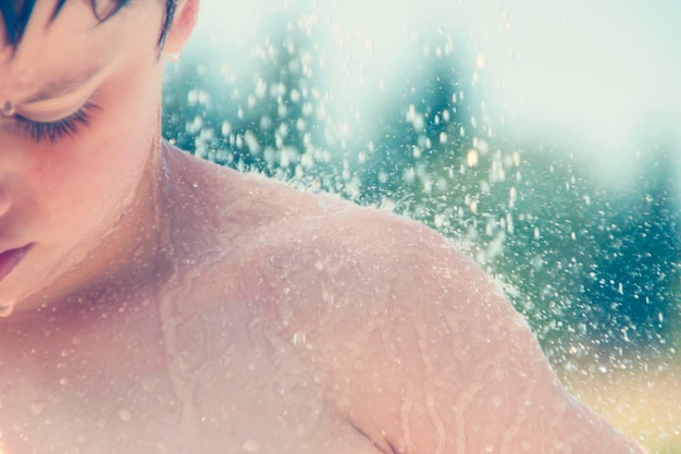 Photo close-up of shirtless boy during rainy season