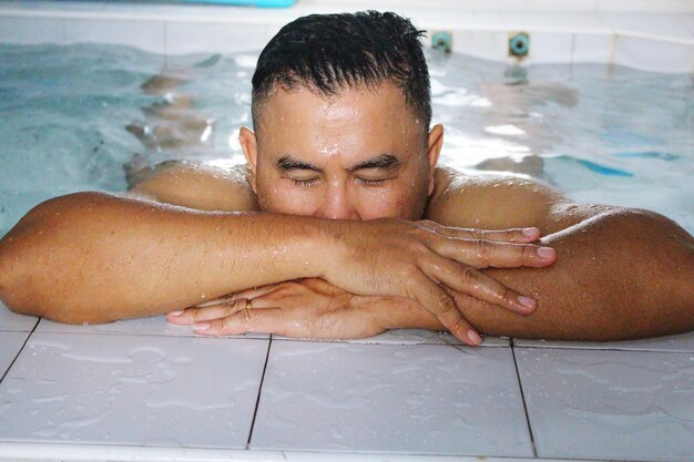 Foto close-up di un uomo senza camicia con gli occhi chiusi in piscina