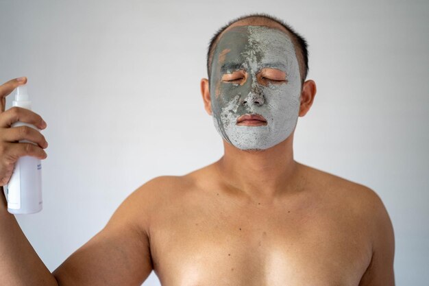 Close-up di un uomo senza camicia con una maschera facciale su uno sfondo bianco
