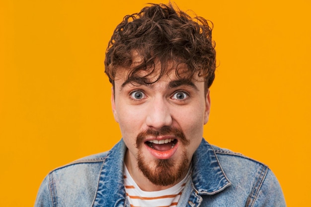 Close up of a shocked young bearded man casually dressed standing isolated