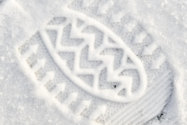 Close-up of a shoe print in the snow, top view of a boot footprint.