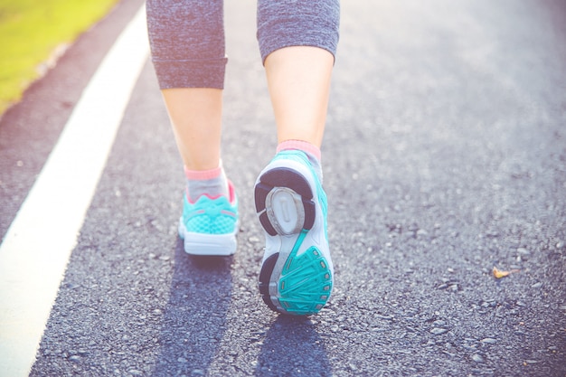 Close up on shoe, Runner athlete feet running on road under sunlight in the morning.