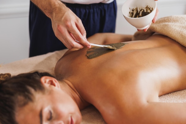 Close-up shoot of a woman enjoying during a seaweed mud treatment at the beauty salon.