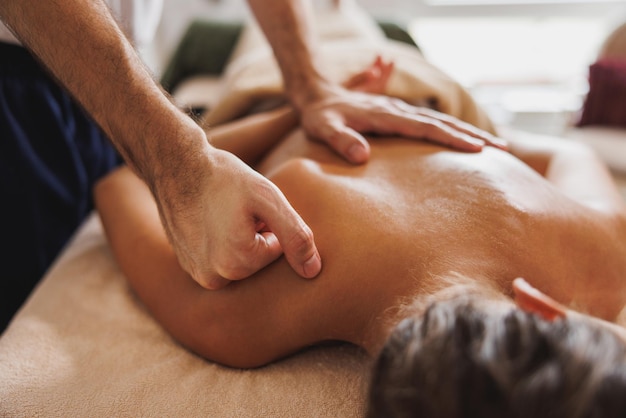 Close-up shoot of a young woman enjoying back massage at the\
beauty salon.