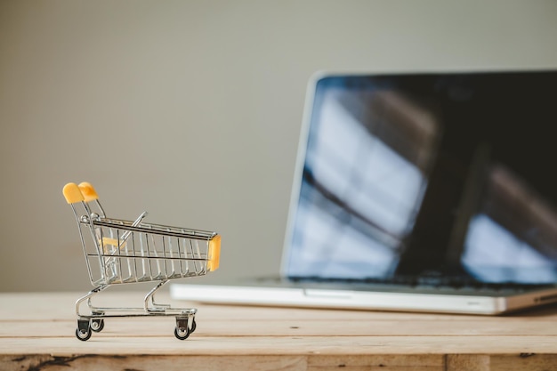 Photo close-up of shopping cart and laptop on table