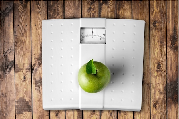 Close-up shot of  Bathroom scale, apple on white