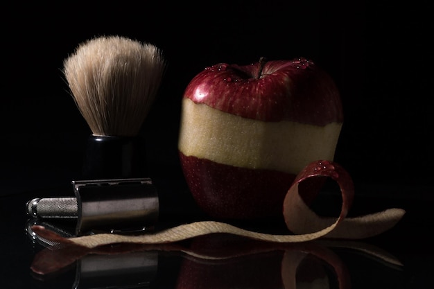 Close up shot of beard shaving brush and an apple peeling with razor