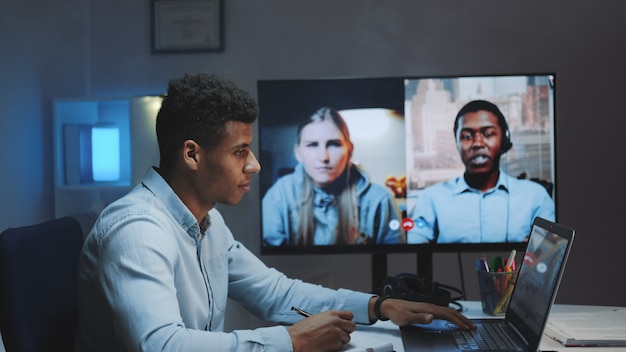 Close-up shot of black chief manager making video call on big
monitor with colleagues on quarantine