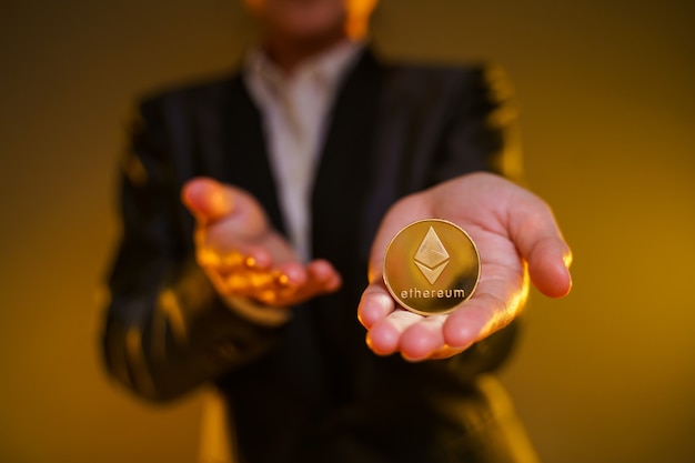 Close up shot of Business woman in black suit holding golden coin isolated on background.