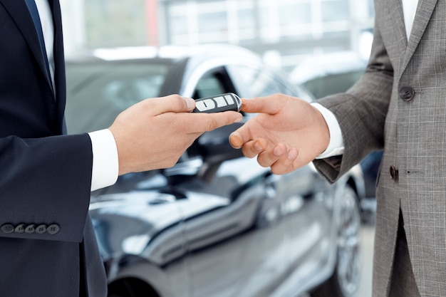 Close up shot of a car dealer passing car keys to the customer