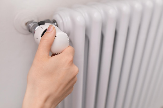 Close up shot of Caucasian females hand adjusting radiator temperature using thermostat