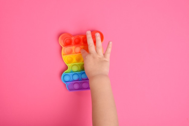 A close-up shot of children's hands playing with the popular pop It fidget toy. A child with a colorful flexible touch toy pop it.