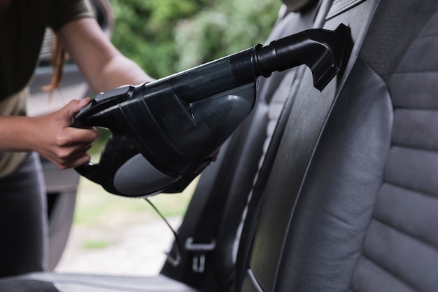 Foto colpo del primo piano che pulisce l'automobile con l'aspirapolvere